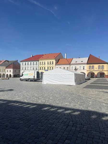 Épülő fehér rendezvénysátor és Ambitent furgon Jičín főterén.