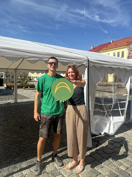 Két ember Ambitent logóval egy fehér rendezvénysátor előtt a jičíni fesztiválon.